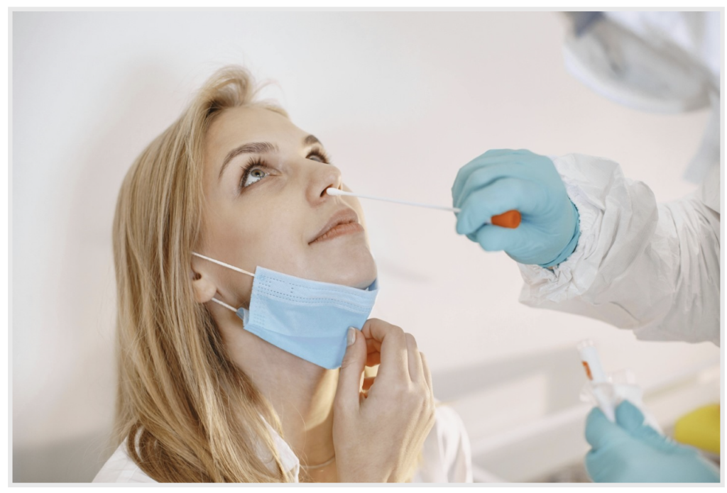 Person receiving a nasal swab from a clinician wearing personal protective equipment.